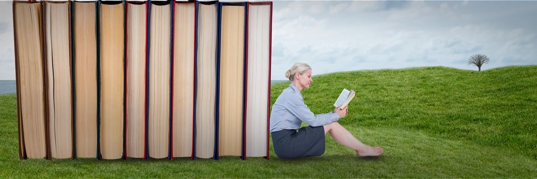 Digital composite of Business woman reading next to books outdoors