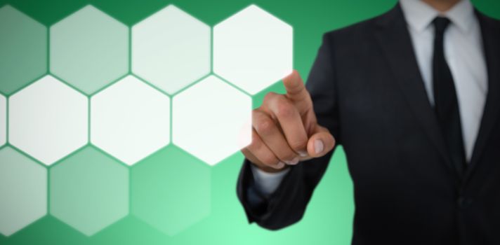 Mid section of businessman with pointing gesture against abstract green background