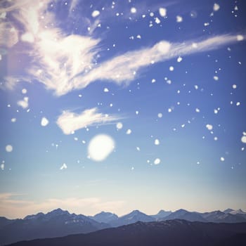 Snow falling against clouds passing over a mountain range