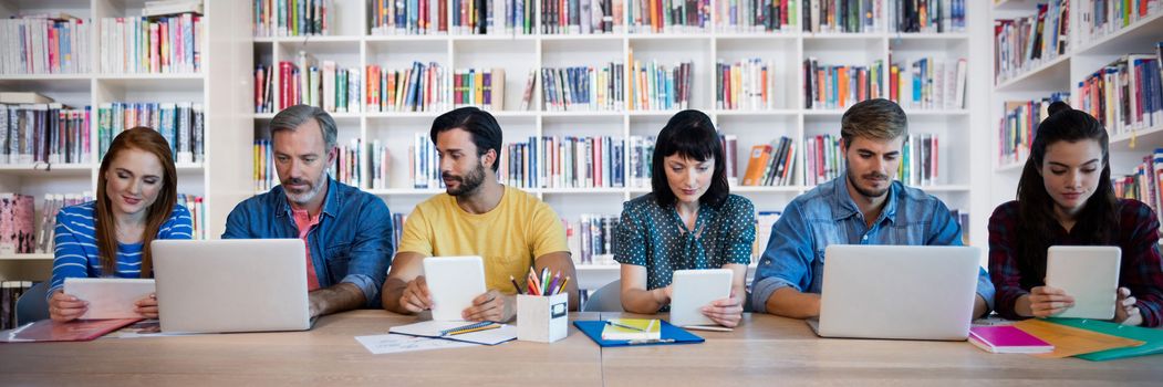 Business people working at table against teacher reading books to her students