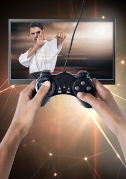 Digital composite of Hands holding gaming controller  with martial arts fighter on television