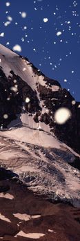 Snow falling against snow capped mountain on a sunny day