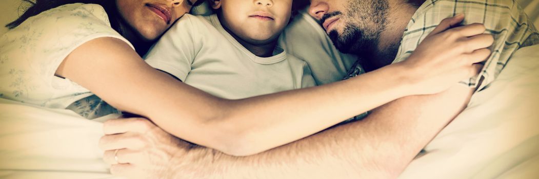 Family sleeping together in bed at home