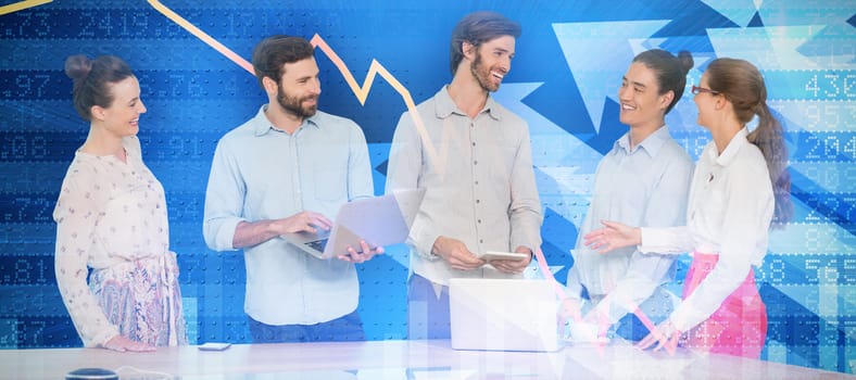 Business people discussing while standing at table against stocks and shares