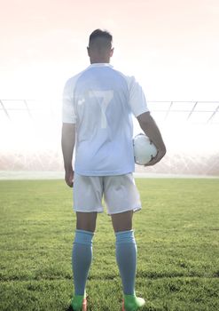 Digital composite of Soccer player on grass with stadium