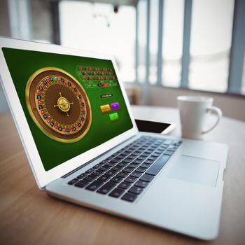Online Roulette Game  against laptop by coffee cup on table
