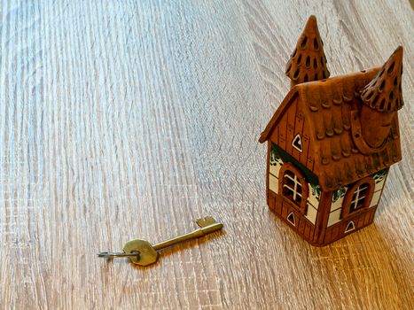 Model of a house and golden key On Wooden Table. Real estate agency, mortgage loan, lottery, buying property.Home loan and investment concept. Copy space