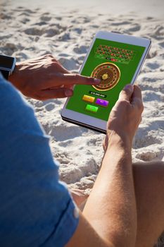 Online Roulette Game  against man using digital tablet on the beach