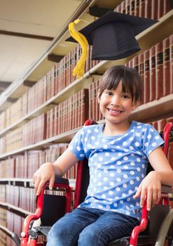 Digital composite of Disabled School girl in education library in wheelchair with graduation hat
