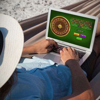 Online Roulette Game  against man using laptop while relaxing on hammock