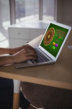 Online Roulette Game  against businesswoman using laptop on wooden desk in office