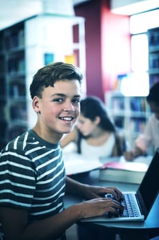 Attentive student using laptop in library at school