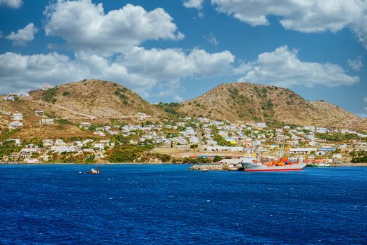 A freighter getting loaded on the coast of a colorful tropical island