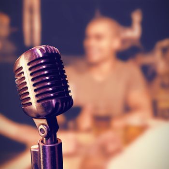 Close-up of microphone  against man having drinks with friends at nightclub