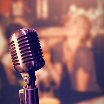 Close-up of microphone  against cheerful friends holding beer mugs at nightclub