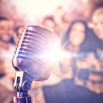 Close-up of microphone  against happy friends holding beer mugs