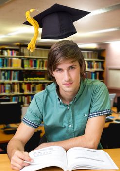 Digital composite of Student man in education library with graduation hat