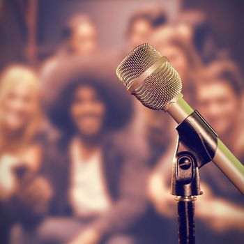 Close-up of microphone  against smiling friends using mobile phones on steps