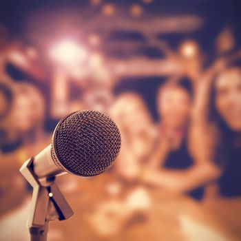 Microphone with stand against happy friends toasting beer glasses at table