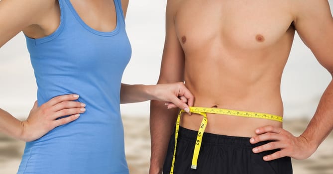 Digital composite of Couple measuring weight with measuring tape on waist on Summer beach