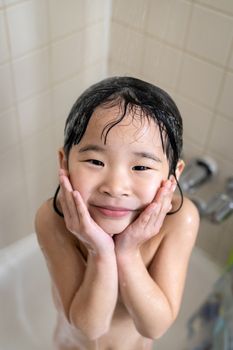 Cute four year old girl taking a relaxing bath with foam in bathroom