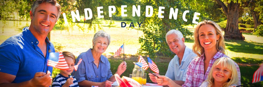 Happy independence day against portrait of family having picnic and holding american flag