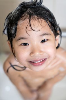 Cute four year old girl taking a relaxing bath with foam in bathroom