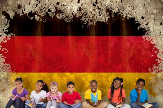Elementary pupils reading books against germany flag in grunge effect