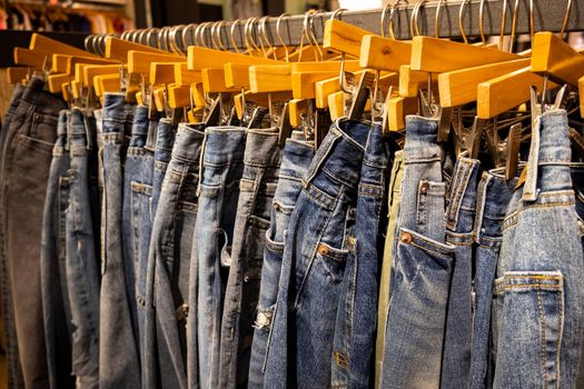 Fashion blue pants and jeans hang on the rack in clothing store. Sale, shopping, fashion, style concept.
