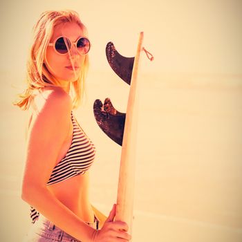 Portrait of beautiful woman holding surfboard at beach during sunny day