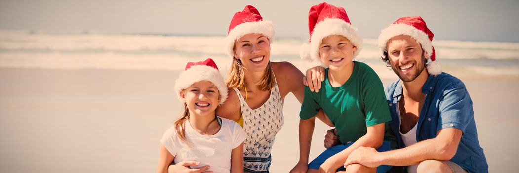 Portrait of smiling family wearing Santa hat at beach during sunny day
