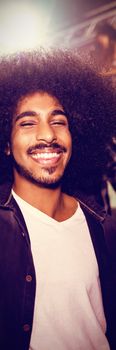 Happy young man with drink dancing in nightclub