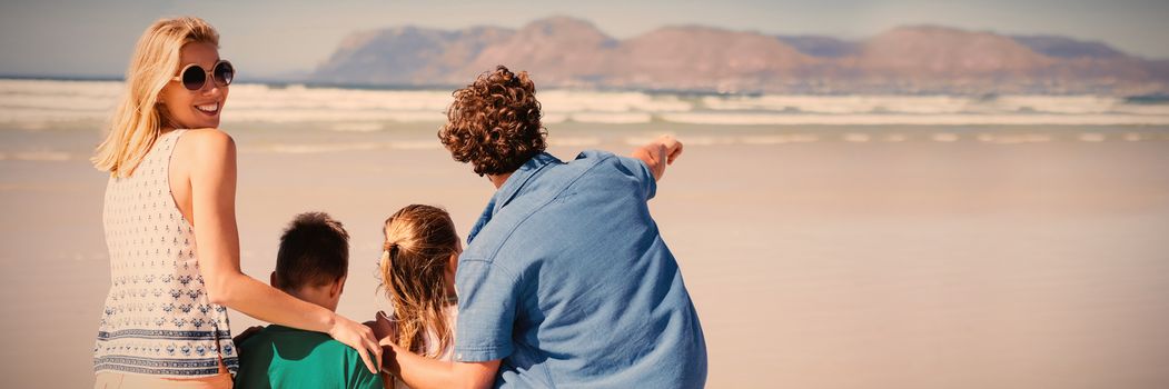 Smiling woman standing with her family at beach during sunny day