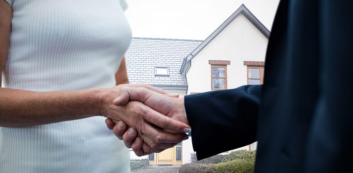 Mid section of business people holding hands against pretty house with a blue and white filter
