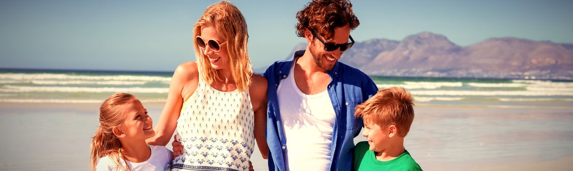 Happy family standing together at beach during sunny day