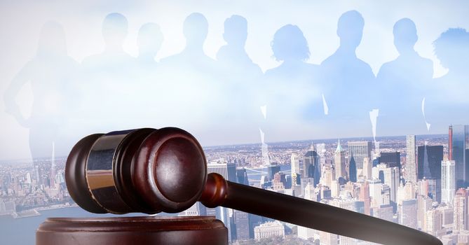 Digital composite of Gavel and people silhouettes over city