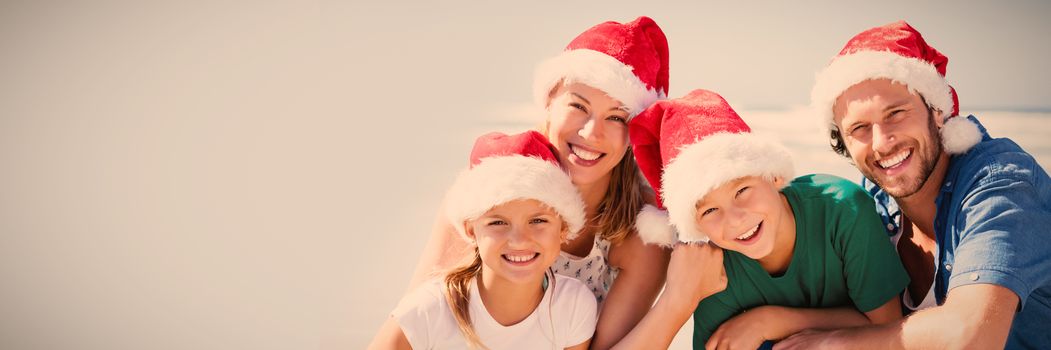 Portrait of happy family wearing Santa hat at beach during sunny day