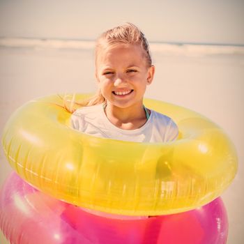 Portrait of girl standing in inflatable rings at beach during sunny day