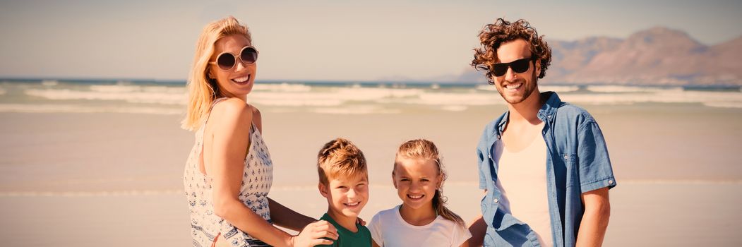 Portrait of smiling family standing on shore at beach during sunny day