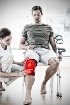 Physiotherapist examining man with crutches against highlighted pain