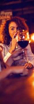 Two beautiful young women having red wine in pub