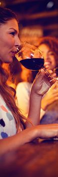 Two beautiful young women having red wine in pub