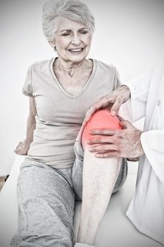 Displeased senior woman getting her knee examined against highlighted pain