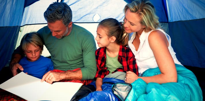 Family reading book together in the tent