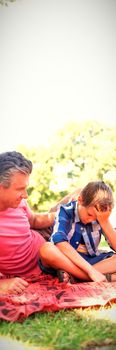 Father consoling his son at picnic in park on a sunny day