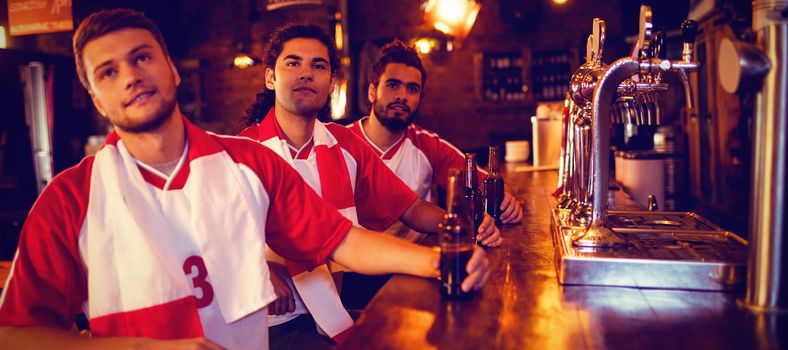 Group of male friends watching football match in pub