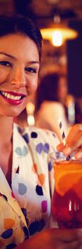 Portrait of young woman having cocktail drink in pub