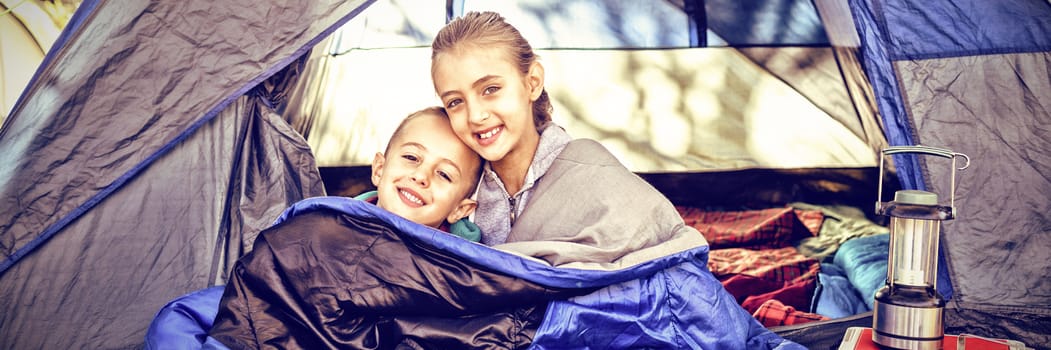 Portrait of happy siblings sitting in the tent