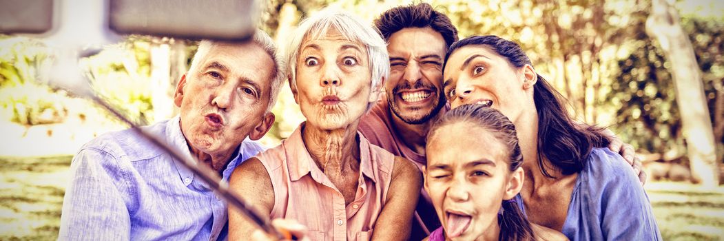 Playful family making funny faces while taking a selfie in the park