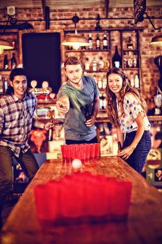 Group of happy friends playing beer pong game in pub